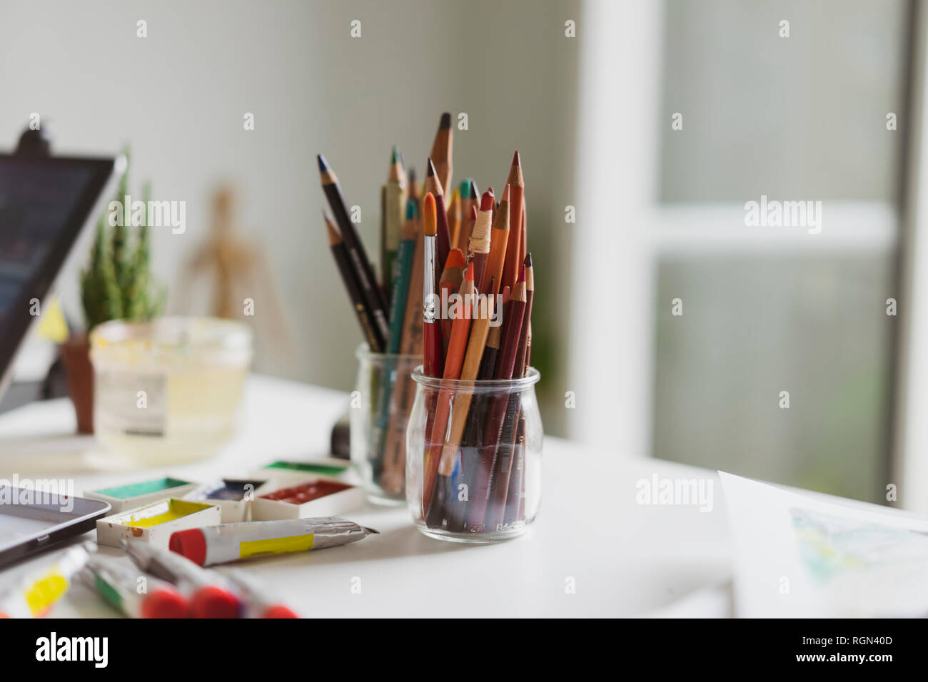 Verres de tubes de peinture, crayons de couleur et aquarelle peint sur illustrator's bureau dans un atelier Banque D'Images