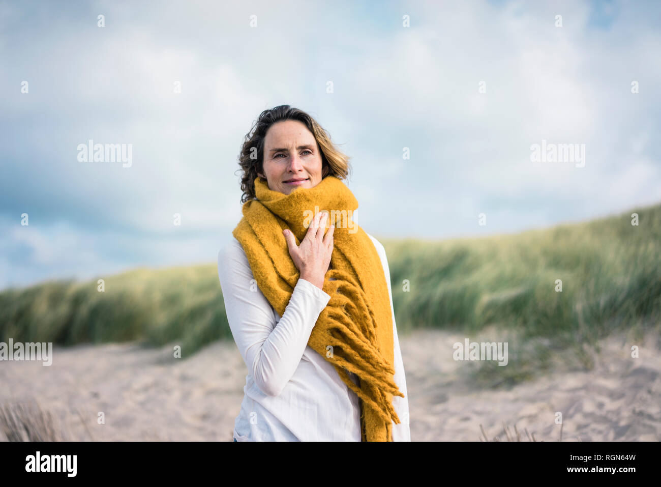 Mature Woman relaxing in the Dunes, appréciant le vent Banque D'Images