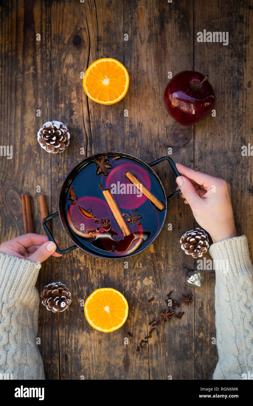 Woman's hands holding marmite de vin chaud avec des tranches d'orange et épices Banque D'Images