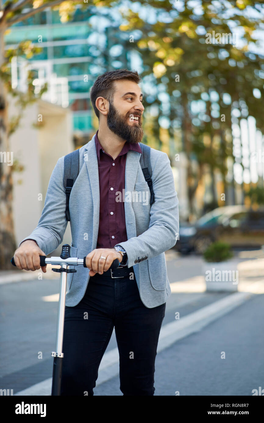 Smiling businessman with scooter sur la voie Banque D'Images