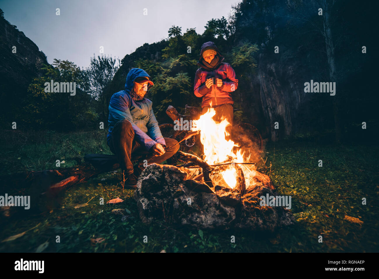 Couple avec avec des vélos à feu de camp Banque D'Images