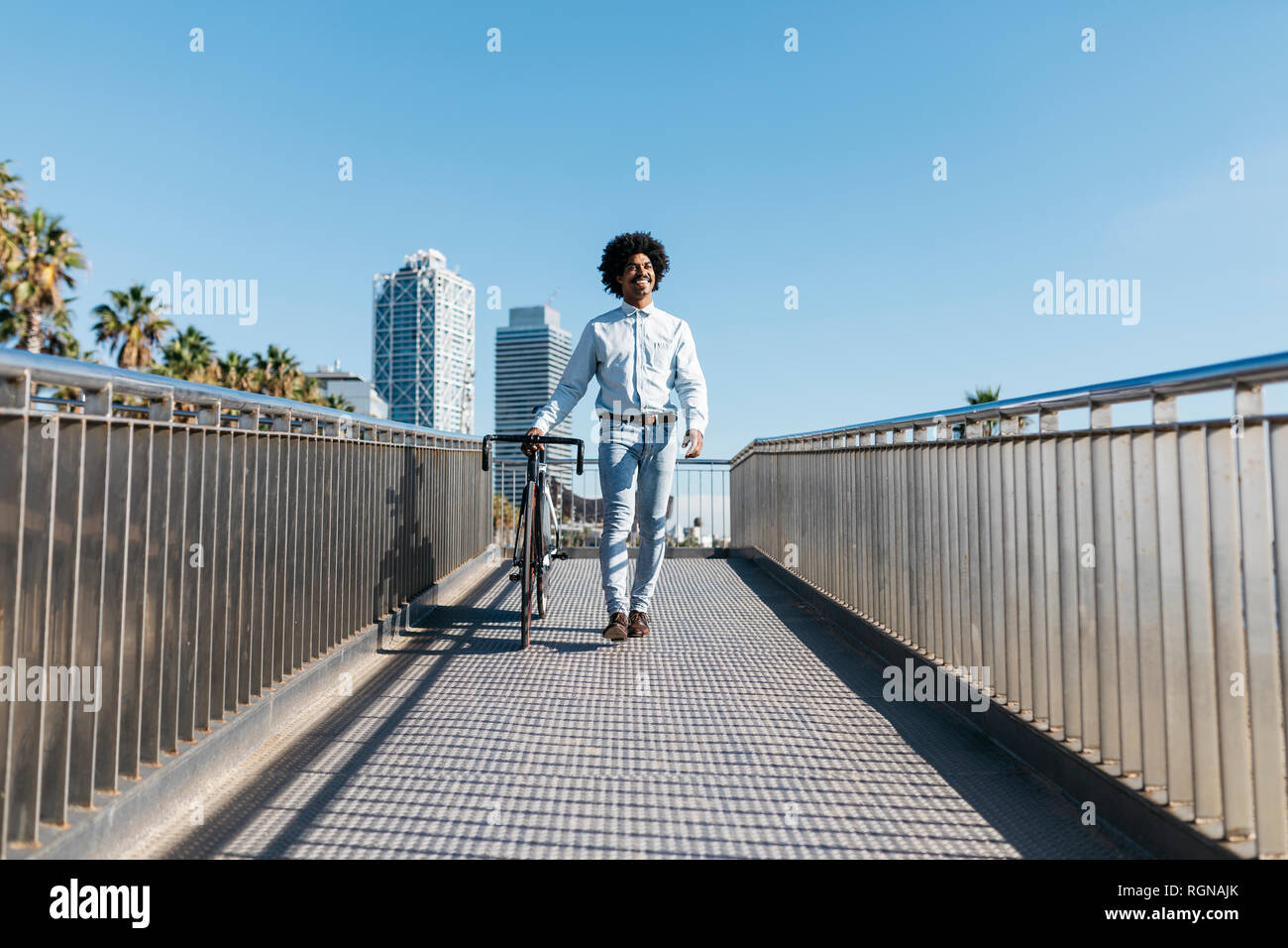 Mid adult man en poussant son vélo sur un pont dans la ville Banque D'Images
