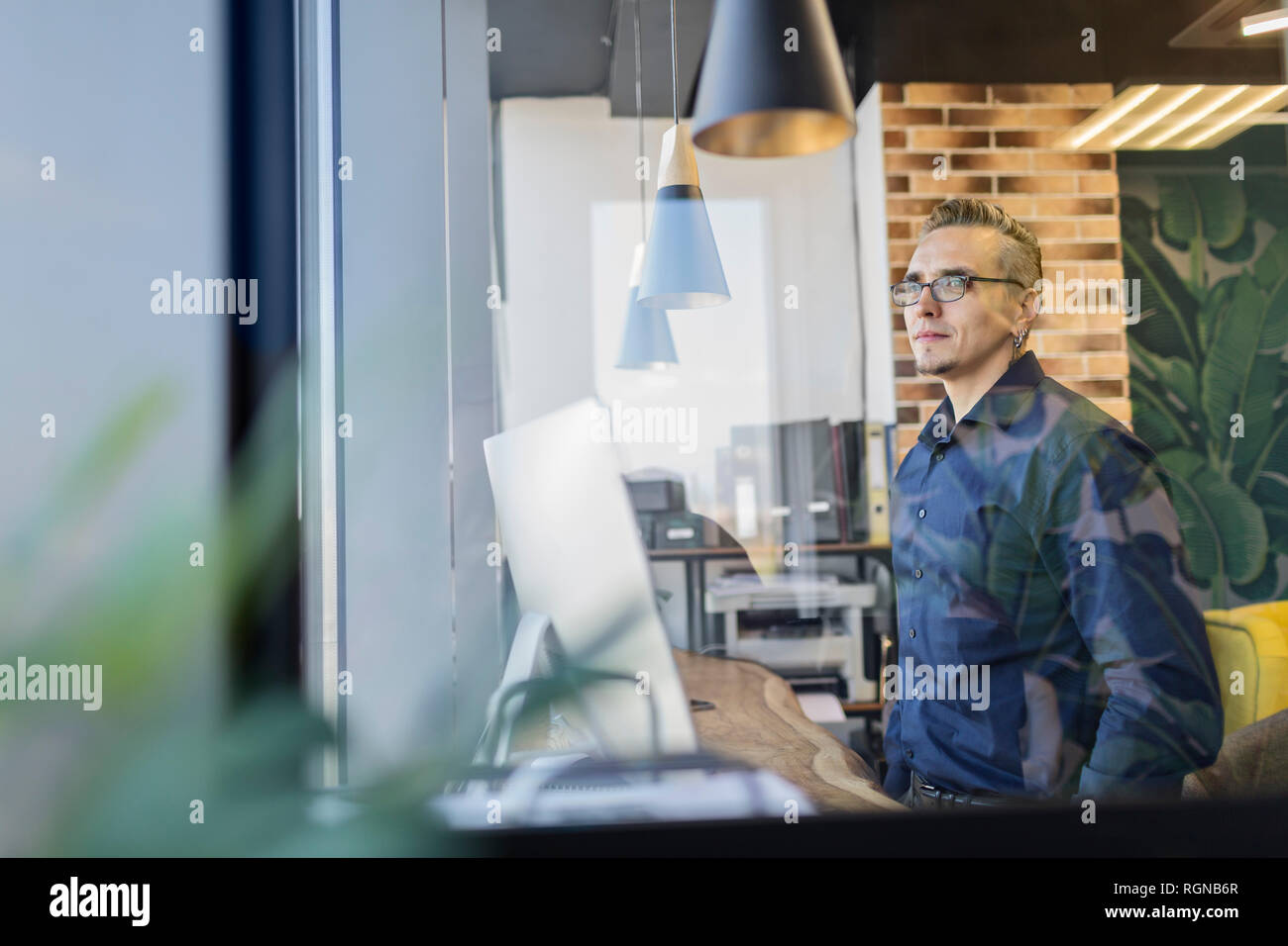 Man Standing in office looking out of window Banque D'Images