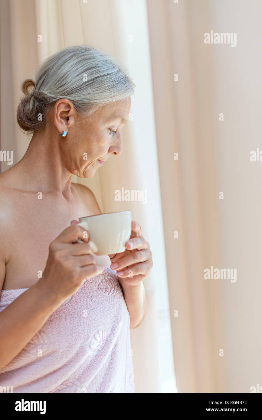 Senior woman wrapped in towel boire le café le matin Banque D'Images