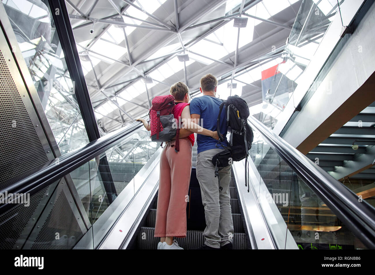 Vue arrière du couple sur l'escalator à l'aéroport. Banque D'Images