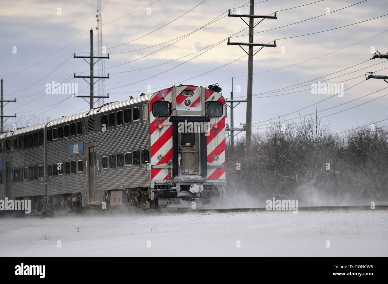 Genève, Illinois, USA. Un train de banlieue de Chicago Metra remue l'entourant la neige comme il passe par Genève, Illinois. Banque D'Images