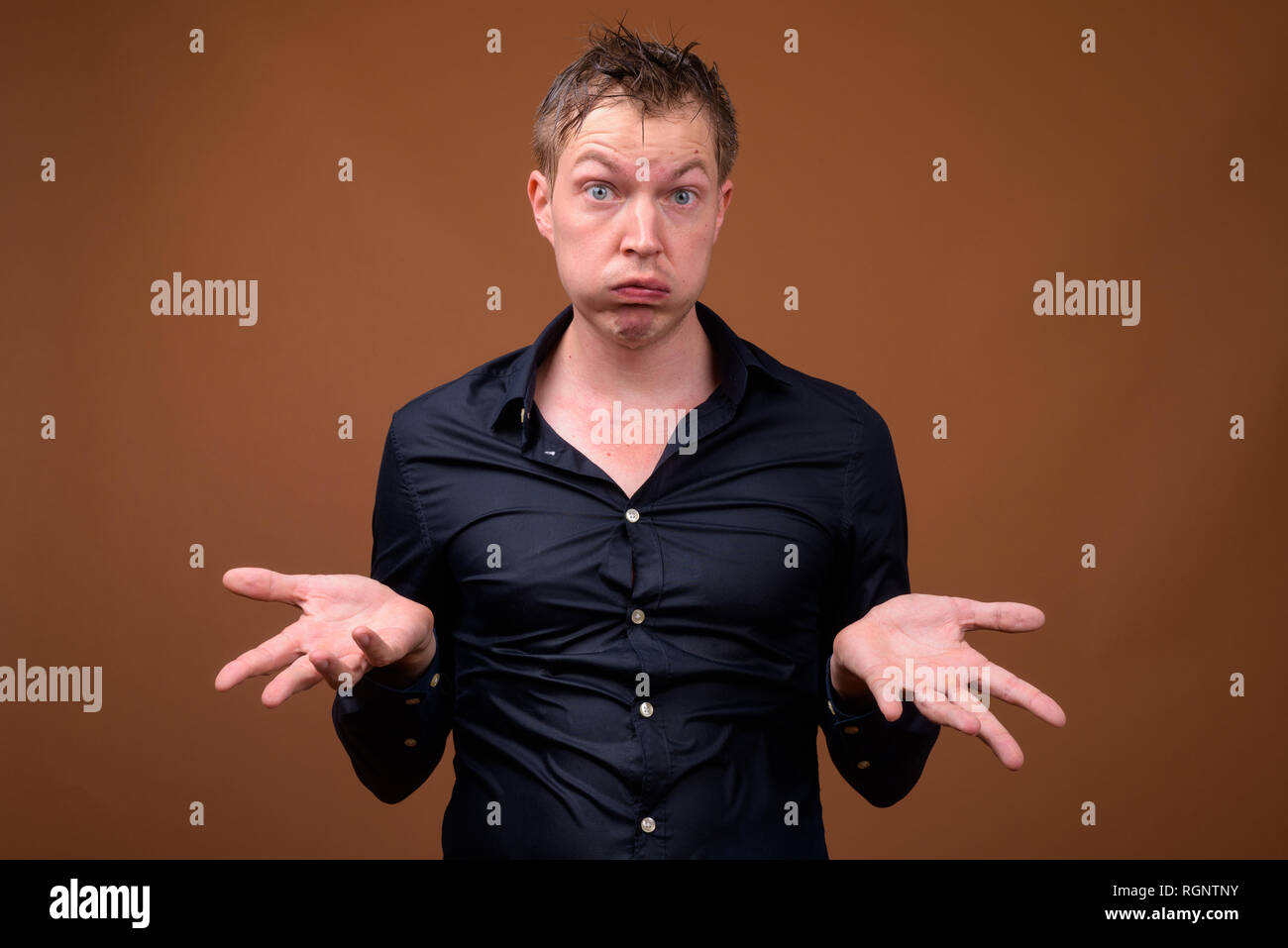 Jeune homme triste dans des vêtements mouillés en haussant les épaules Banque D'Images