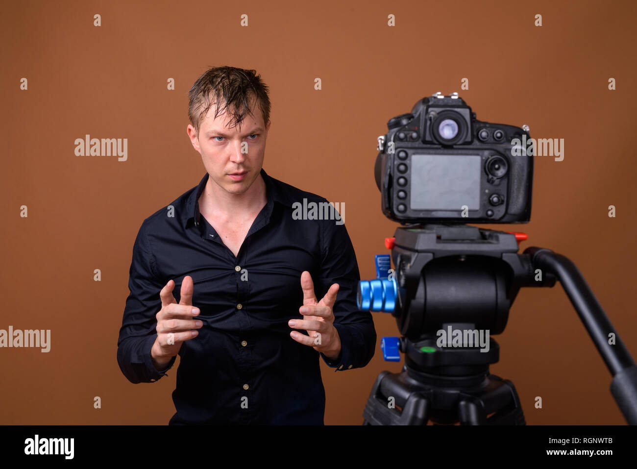 Jeune homme influenceur vlogging avec votre appareil photo reflex numérique en studio Banque D'Images