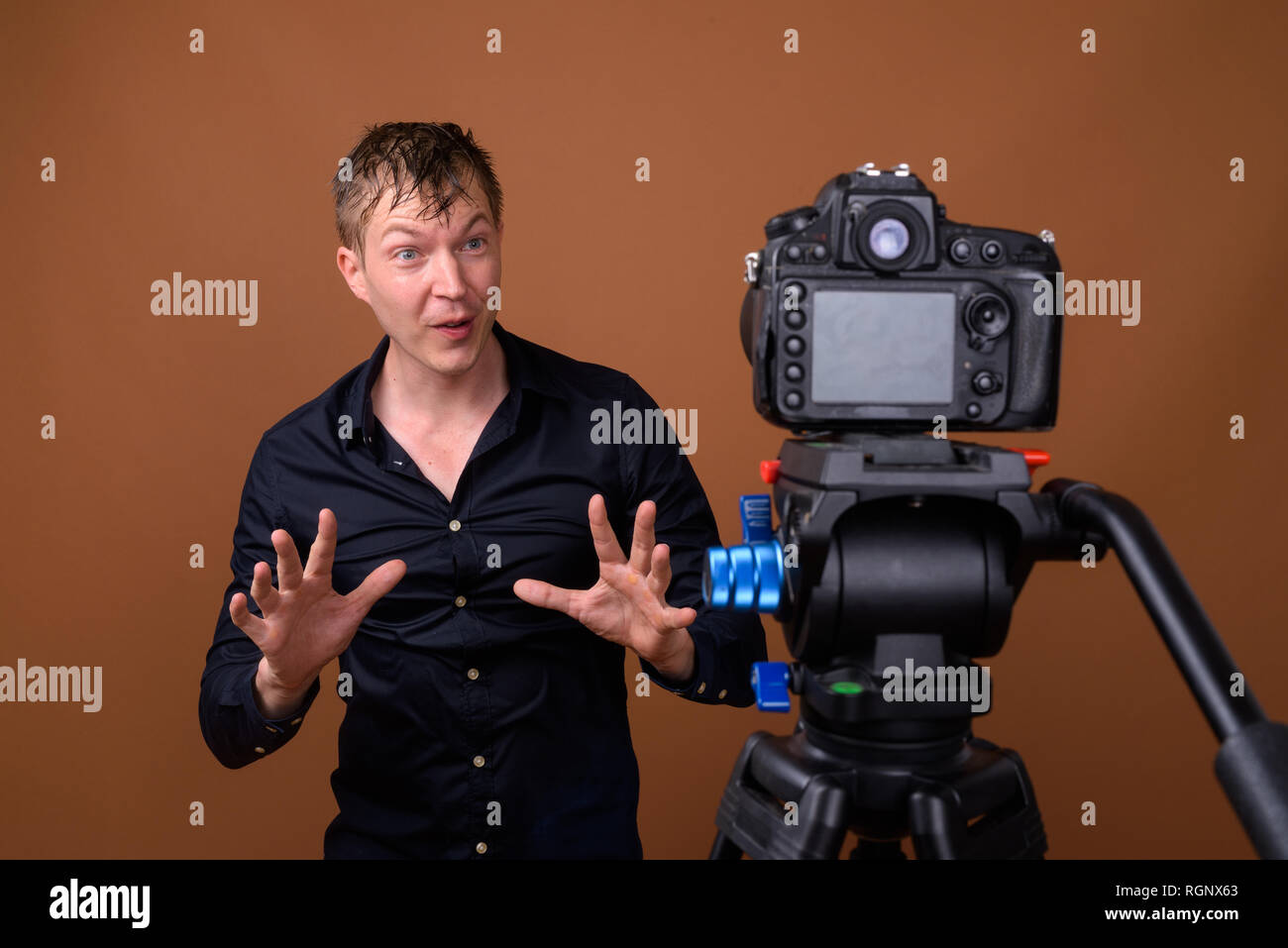 Homme heureux influenceur vlogging avec votre appareil photo reflex numérique en studio Banque D'Images