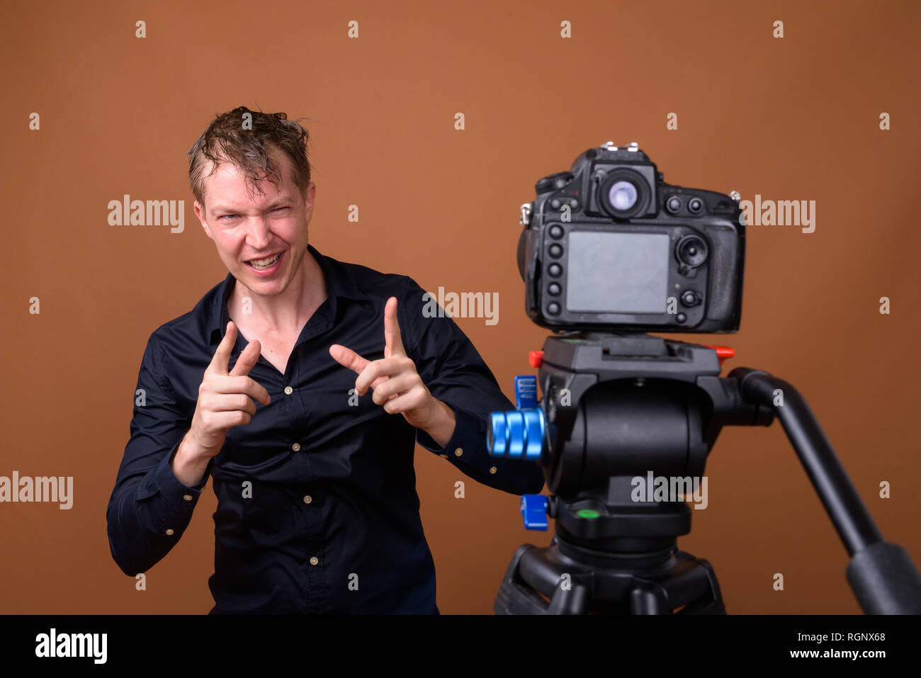 Homme heureux influenceur vlogging avec votre appareil photo reflex numérique en studio Banque D'Images