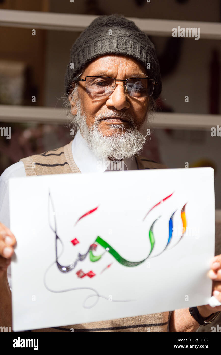 Dubaï, Émirats arabes unis - Février 14, 2018 : Local calligraphe holding paper avec signe à Dubaï boutique de calligraphie, Emirats Arabes Unis Banque D'Images