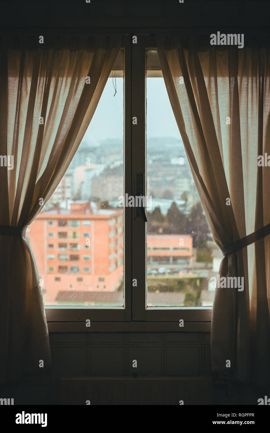 Fenêtre avec des rideaux dans la pièce sombre de l'appartement et vue magnifique de la ville Banque D'Images