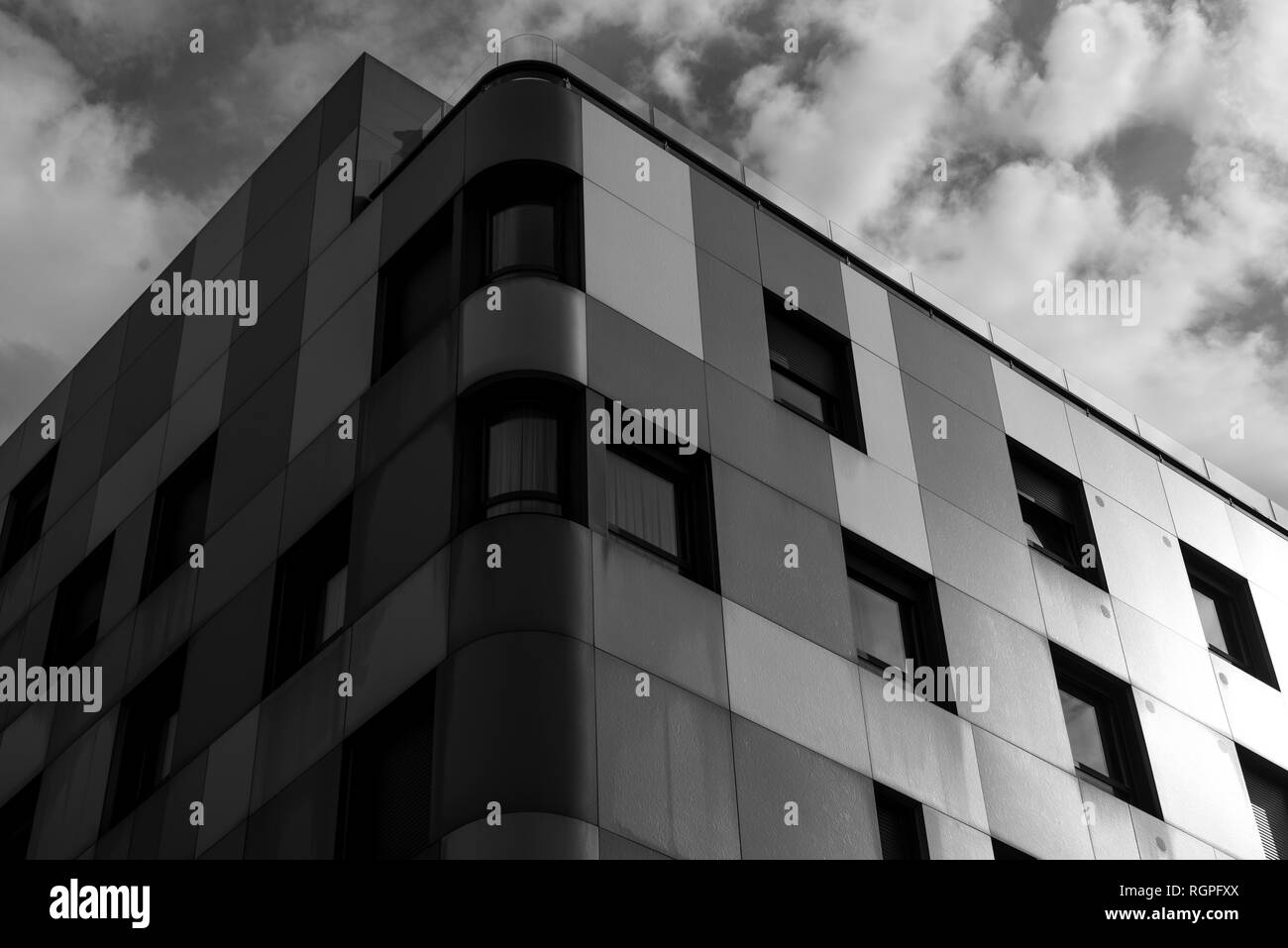 Le noir et blanc à partir de ci-dessous façades de bloc d'appartements avec de nombreuses fenêtres et ciel nuageux Banque D'Images