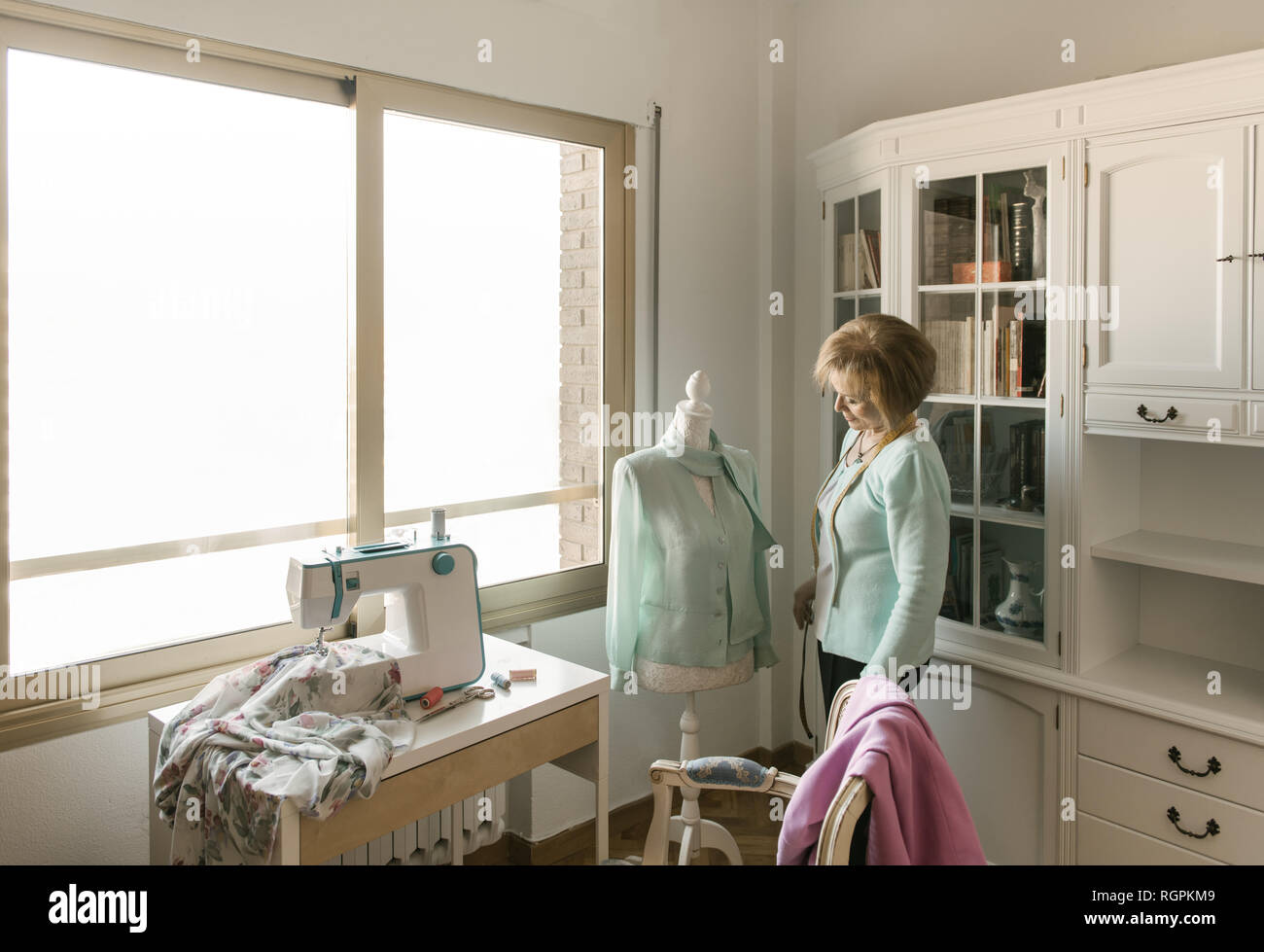 Réglage de la belle femme hauts vêtements ornementaux sur mannequin tout en travaillant en atelier confortable Banque D'Images