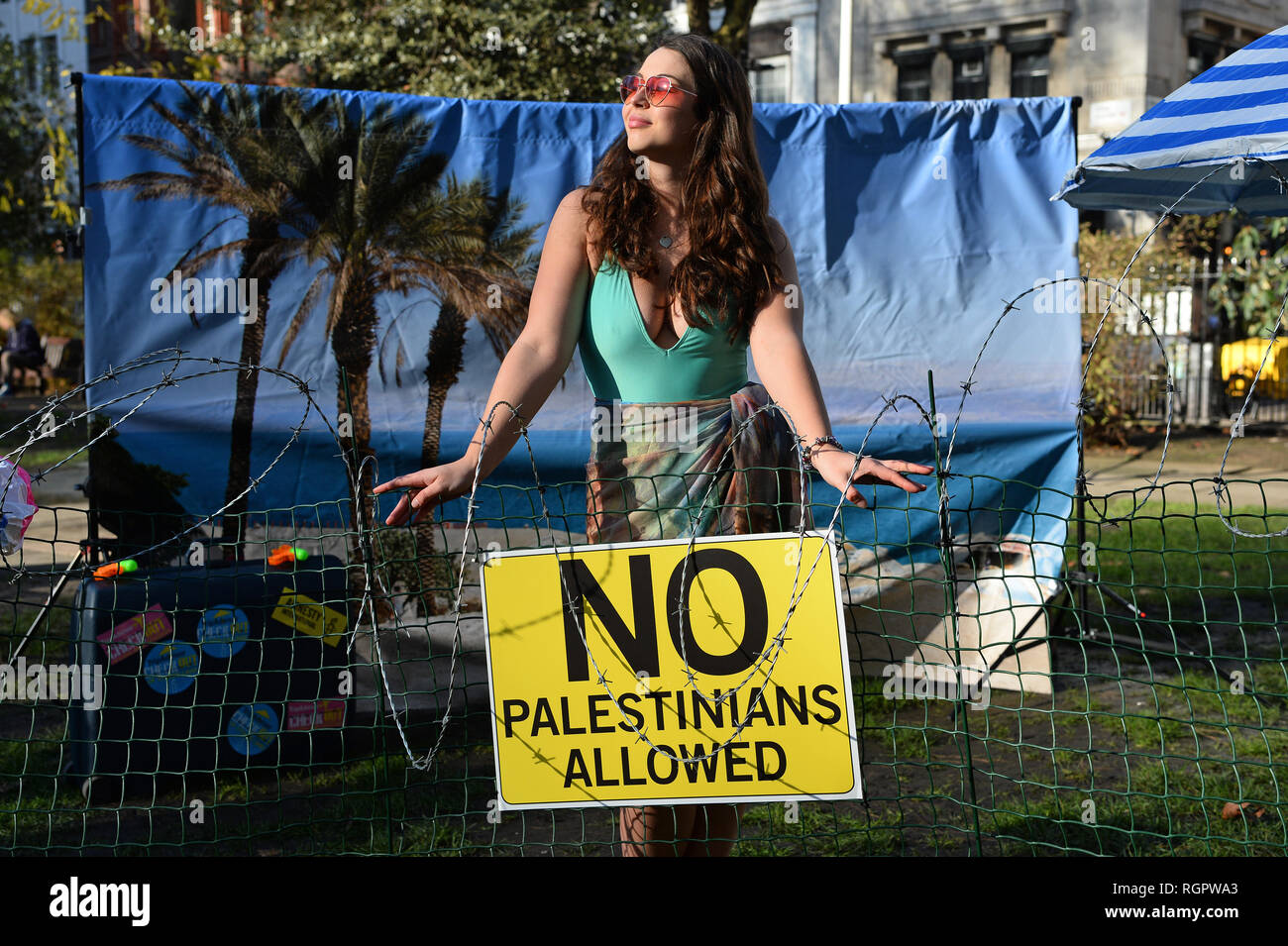 Un modèle se dresse sur un 'Beach' de barbelés à l'extérieur des bureaux de TripAdvisor à Soho Square, centre de Londres, dans le cadre d'une campagne d'Amnesty International demande à l'entreprise et d'autres compagnies de voyage pour arrêter l'inscription chambres et activités dans les colonies de peuplement israéliennes dans les territoires palestiniens. Banque D'Images