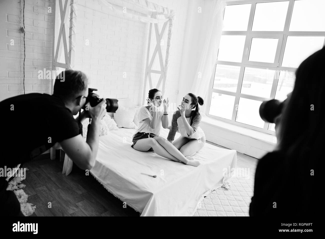 L'équipe de tournage, deux photographes sur studio twins les filles pendant qu'ils font leur propre masque crème. Photographe professionnel sur le travail. Banque D'Images