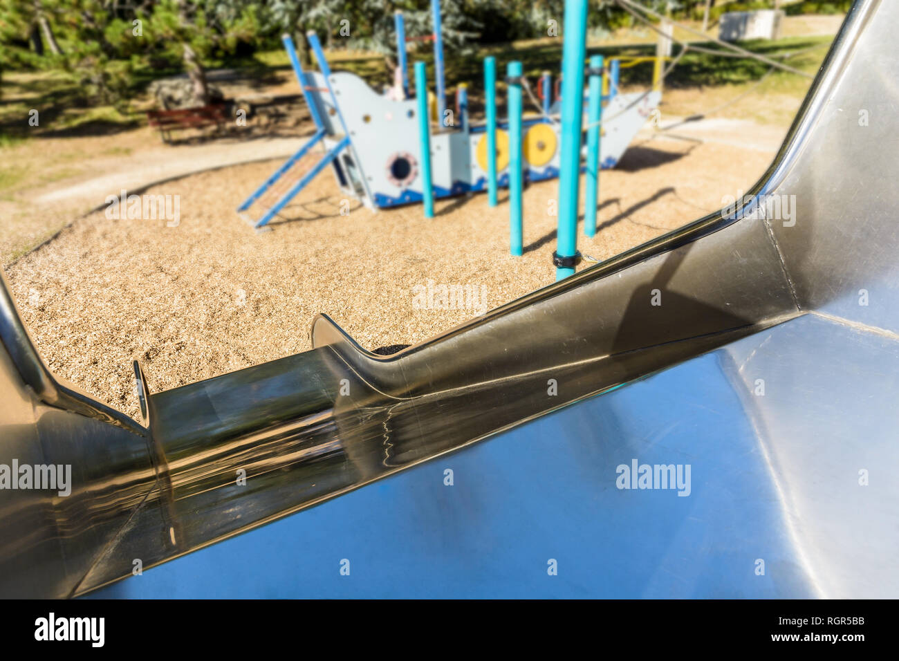 Première personne vue depuis le haut d'une aire de jeux en acier inoxydable diapositive d'une aire de jeux pour enfants avec un bateau pirate dans l'arrière-plan. Banque D'Images
