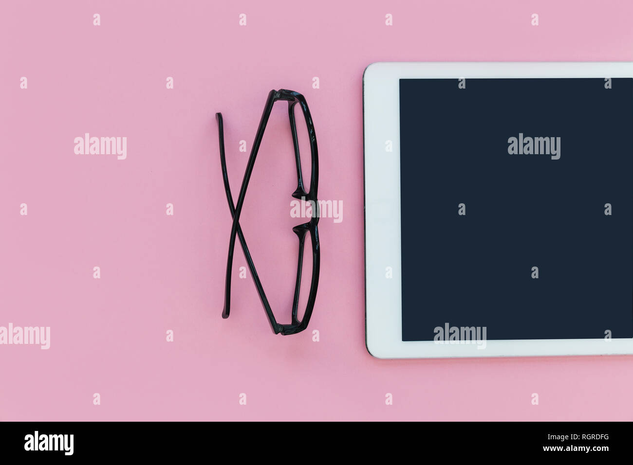 Ordinateur tablette blanc avec lunettes de lecture sur fond de couleur rose bureau minimal Banque D'Images