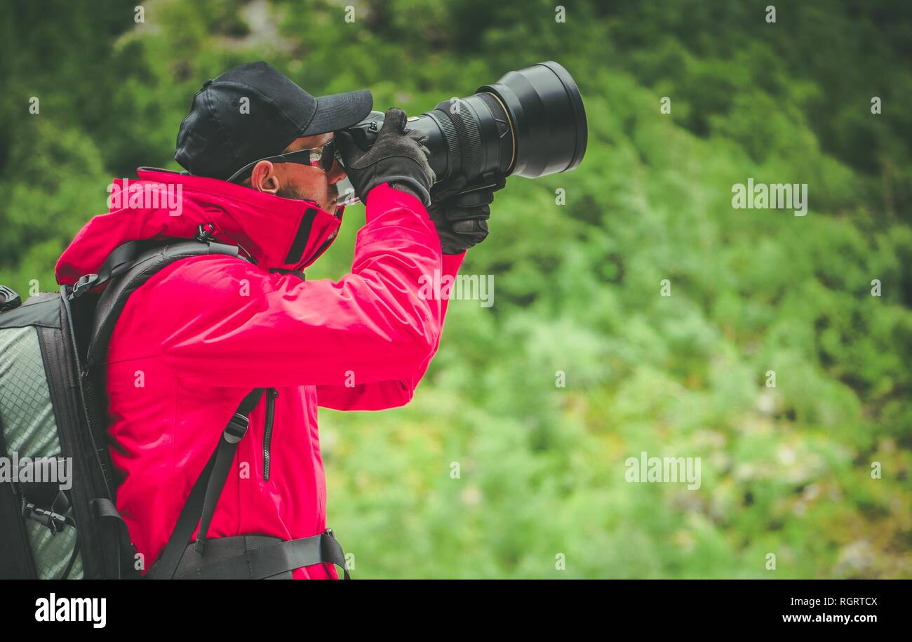 Photographe Nature caucasienne avec grand téléobjectif en tenant les photos à l'extérieur. Banque D'Images