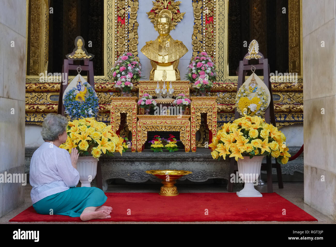 Une femme priant devant un buste de l'ancien roi Bhumipol Adulyadej, Wat Boworniwet, Bangkok, Thaïlande Banque D'Images
