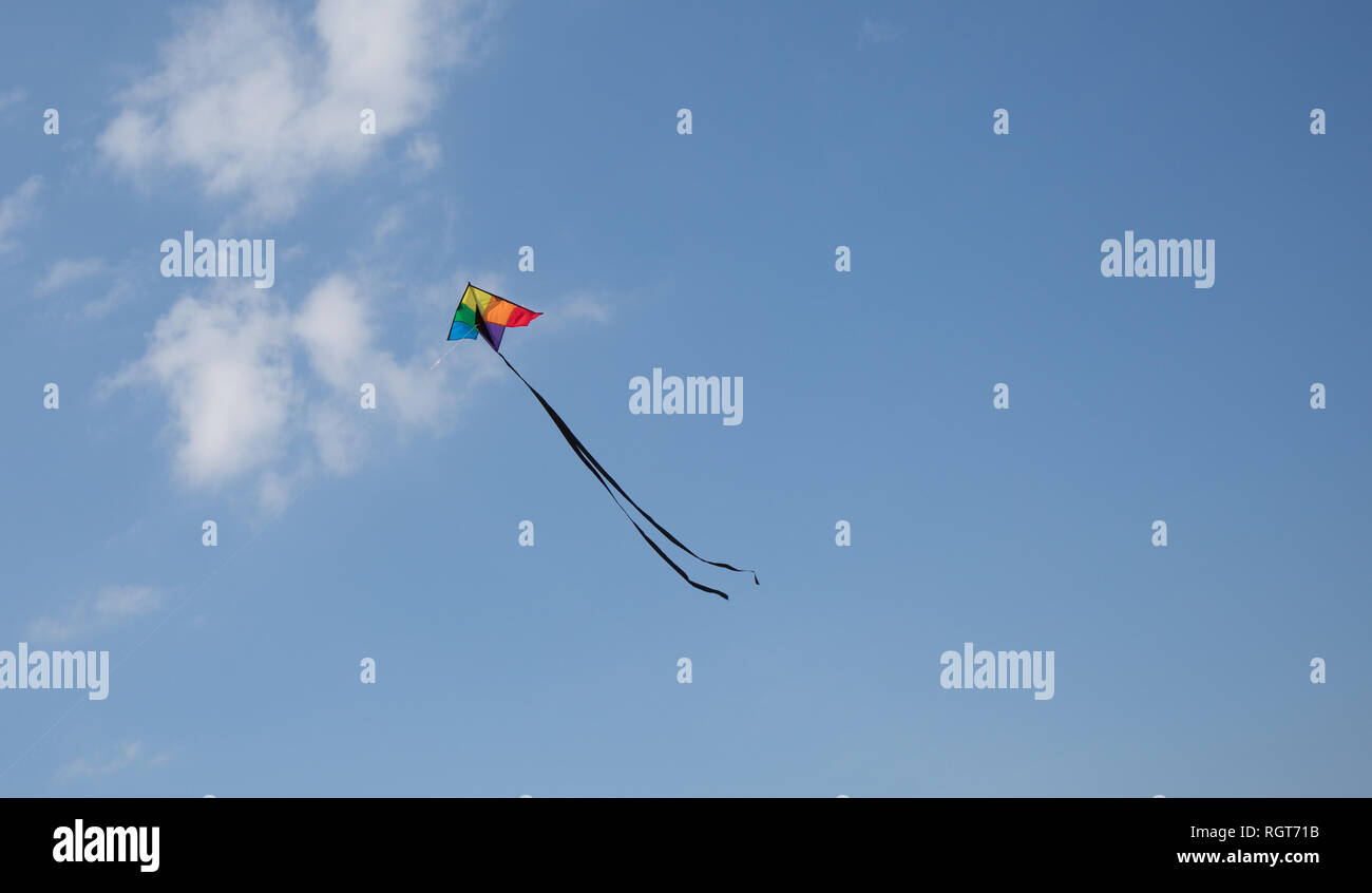 Un cerf-volant de couleur arc-en-ciel élevée en flèche dans le ciel bleu sur une journée ensoleillée. Banque D'Images