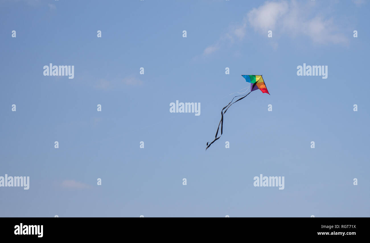 Un cerf-volant de couleur arc-en-ciel élevée en flèche dans le ciel bleu sur une journée ensoleillée. Banque D'Images