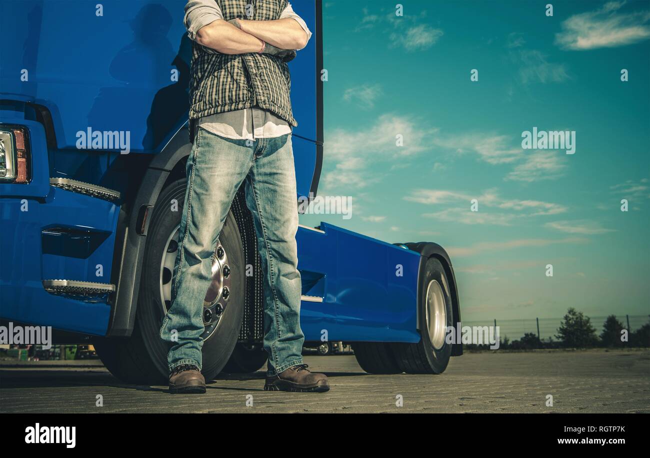 Semi Truck et le pilote. Fier Caucasian Trucker avec mains croisées. L'industrie automobile. Banque D'Images