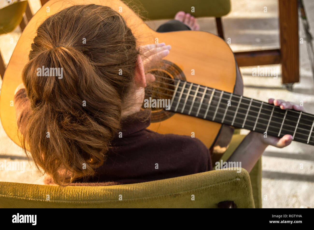 Petite fille aux pieds nus jouant de la guitare à l'extérieur durant une  journée ensoleillée. Avec l'enfant assis sur des chaises alors que cochon  apprendre à jouer de la guitare dans l'extérieur