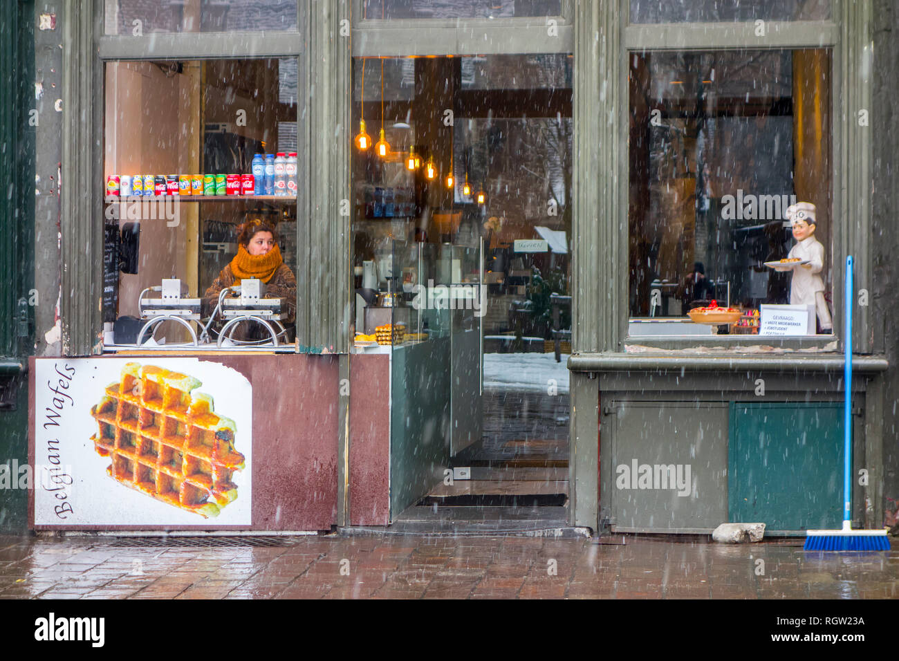 Vendeur de gaufres belges en attente de clients / touristes durant le grésil et neige douche en hiver dans la ville de Gand, Flandre orientale, Belgique Banque D'Images