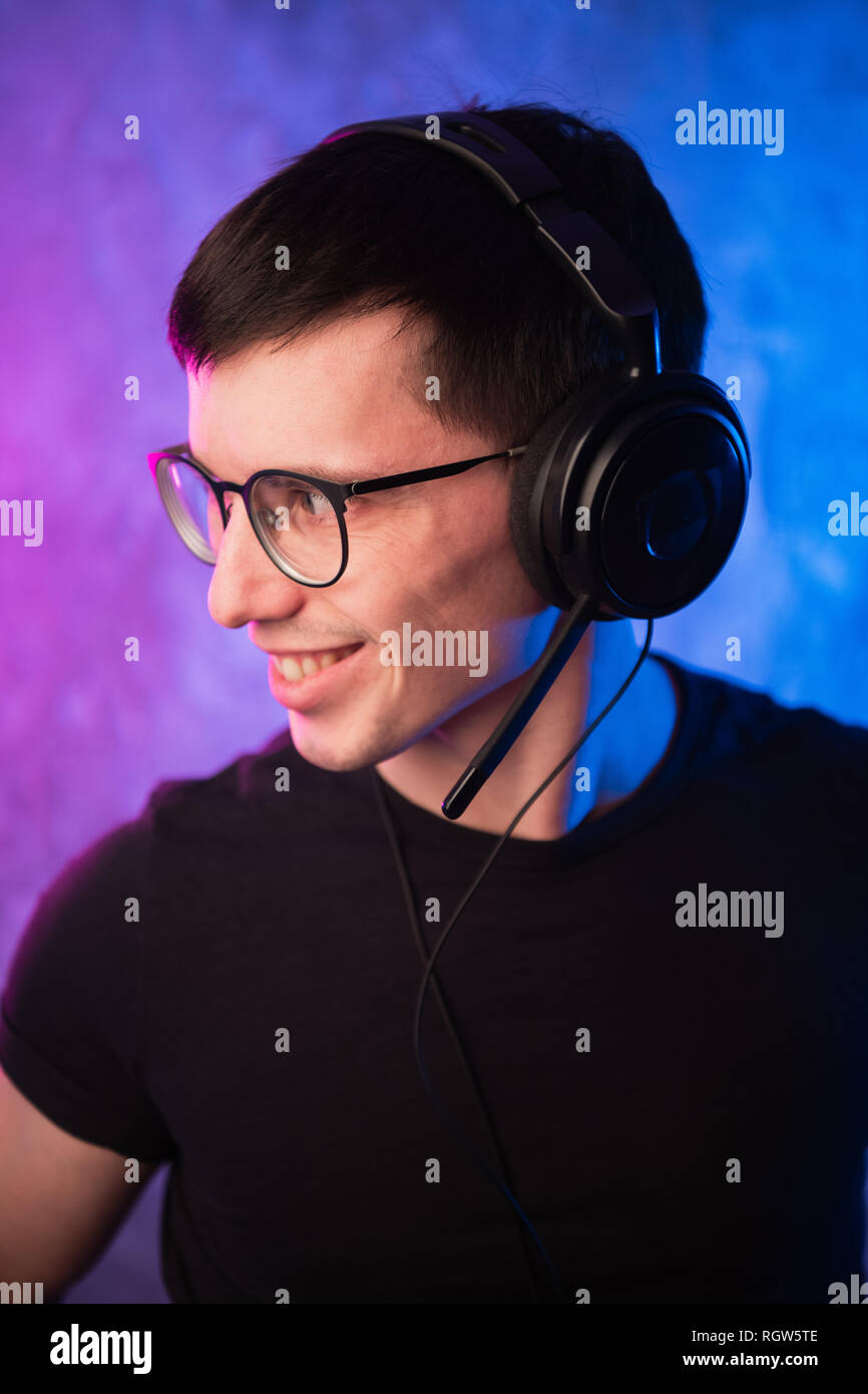 Gamer ou streamer des écouteurs avec microphone sur rose et bleu coloré éclairé au néon wall Banque D'Images