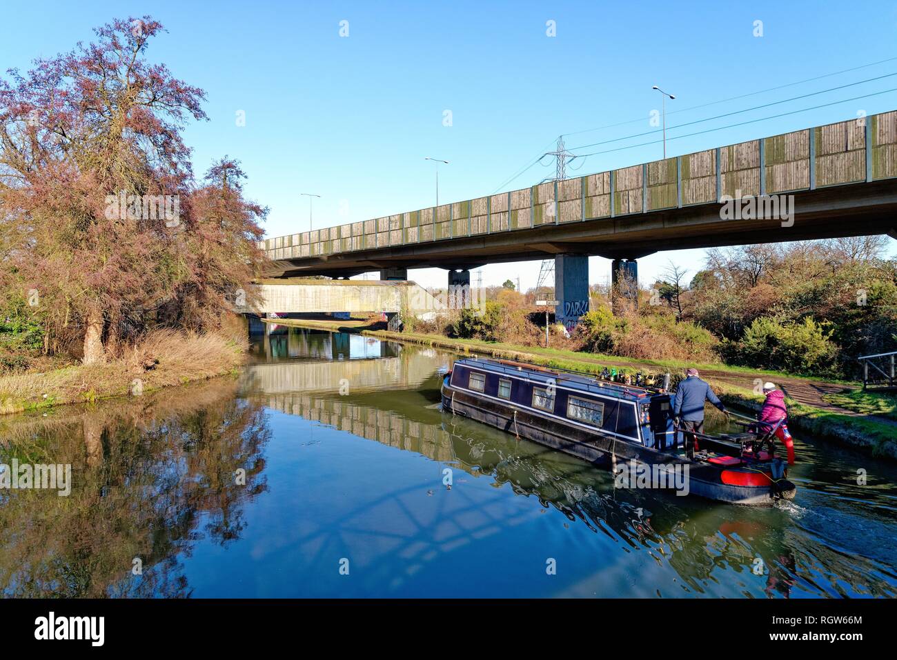 Un petit bateau sur la jonction de la voie navigable Wey et la Basingstoke canal à New Haw, avec l'augmentation de la section de l'autoroute M25,Surrey England Banque D'Images