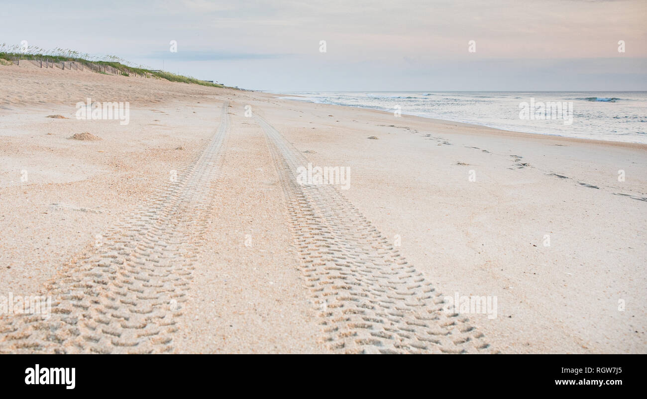 Les marques de pneu dans le sable conduisant au loin sur la plage. Banque D'Images