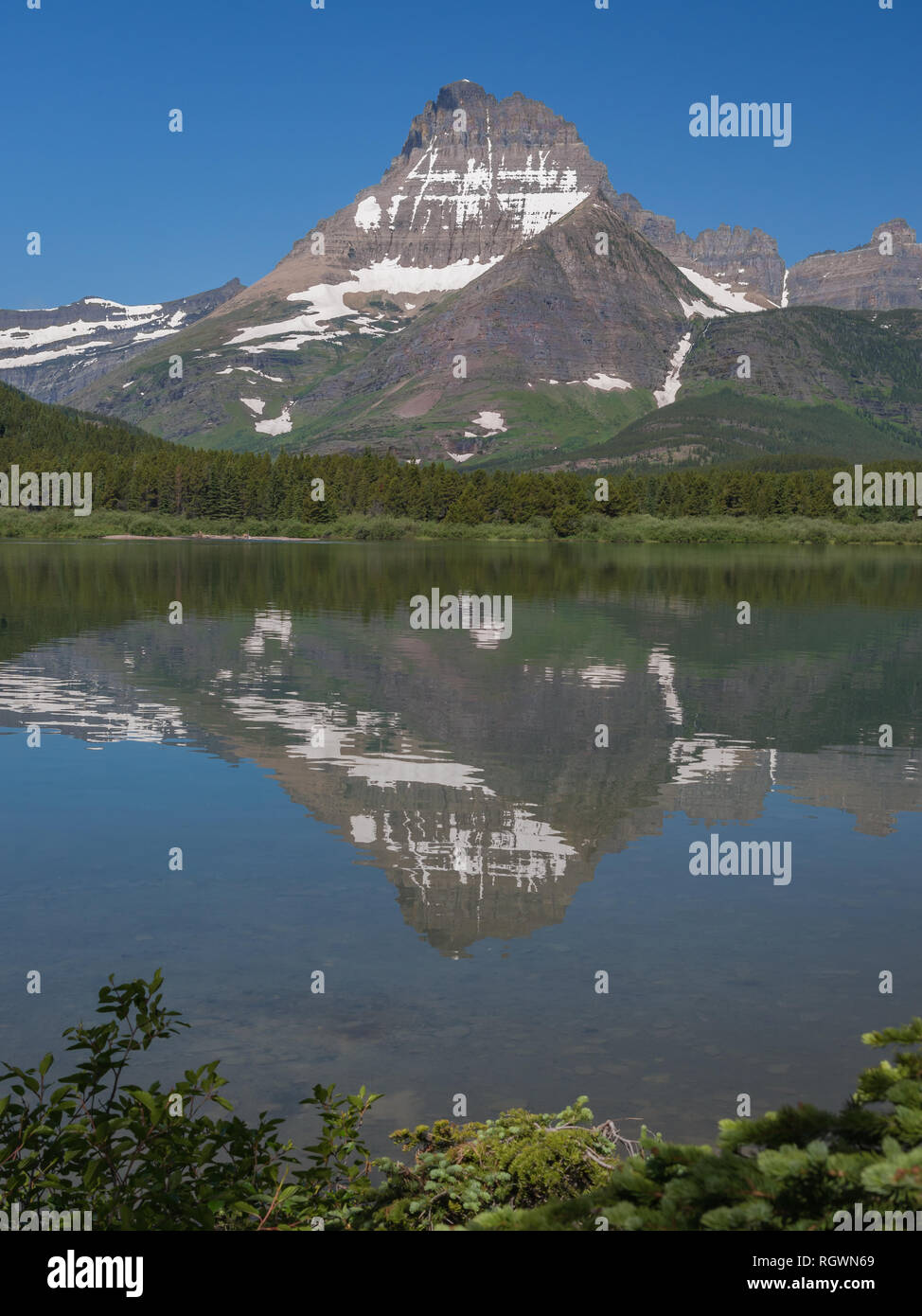 Vertical image du Mont Wilbur avec son sommet, la neige et les glaciers reflète dans l'eau d'un lac de montagne dans le parc national des Glaciers Banque D'Images