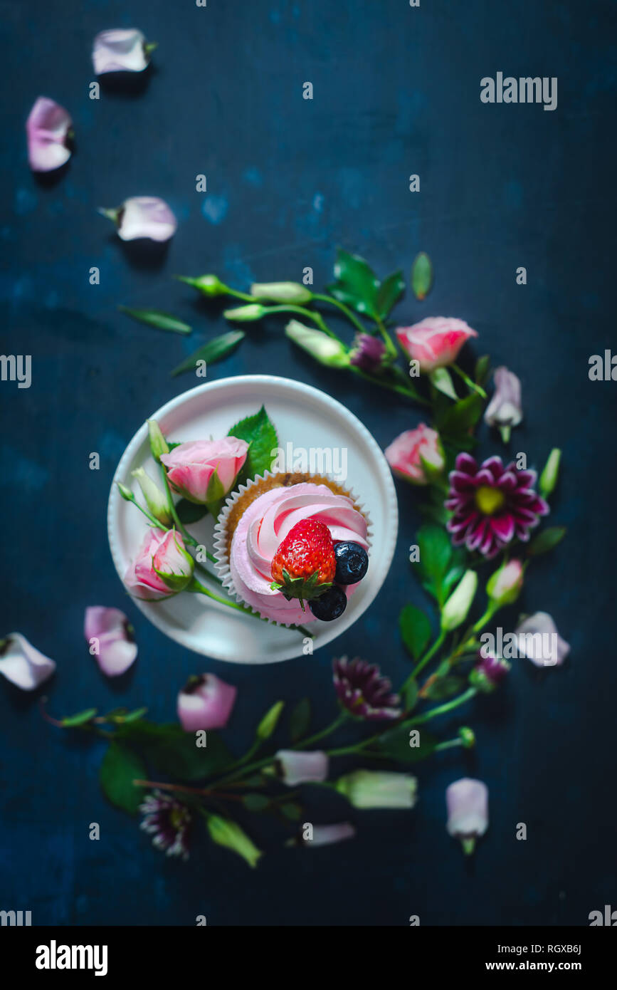 Cupcakes avec fraises et fleurs rose sur un fond sombre. Dessert de printemps concept avec copie espace Banque D'Images