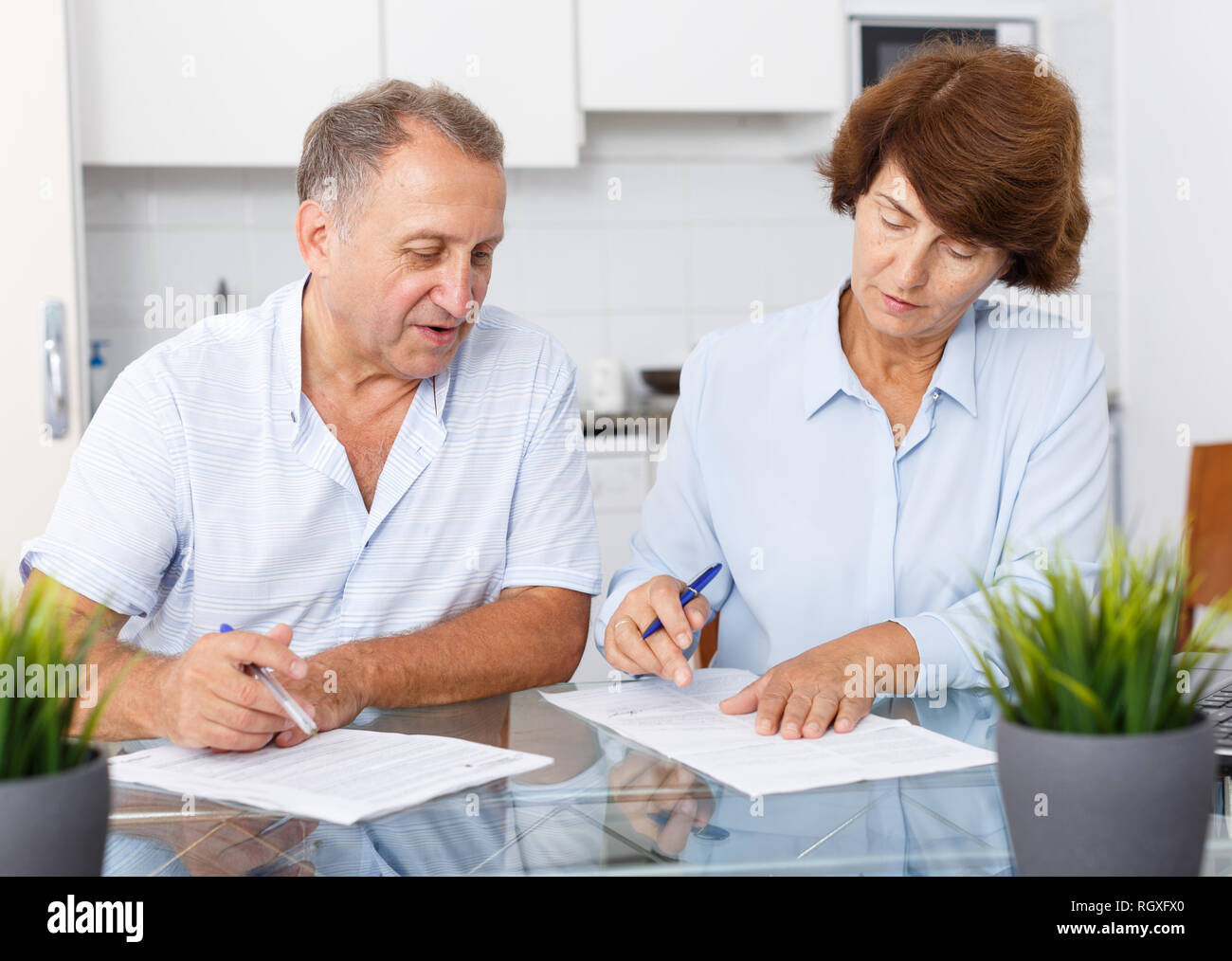 Famille mature couple sitting at table de cuisine et la signature de documents ensemble Banque D'Images