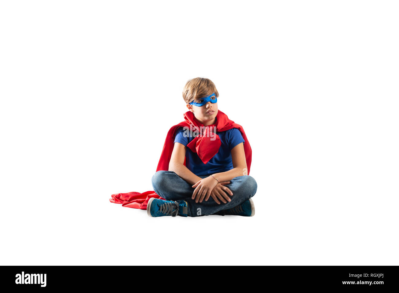 Super Héros kid assis sur un mur que les rêves. Isolé sur fond blanc Banque D'Images