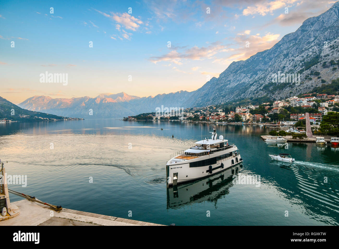 Kotor, Monténégro : un yacht de luxe tire au port tôt le matin, comme le soleil se lève sur les montagnes et les eaux vert émeraude de la baie de Kotor Banque D'Images