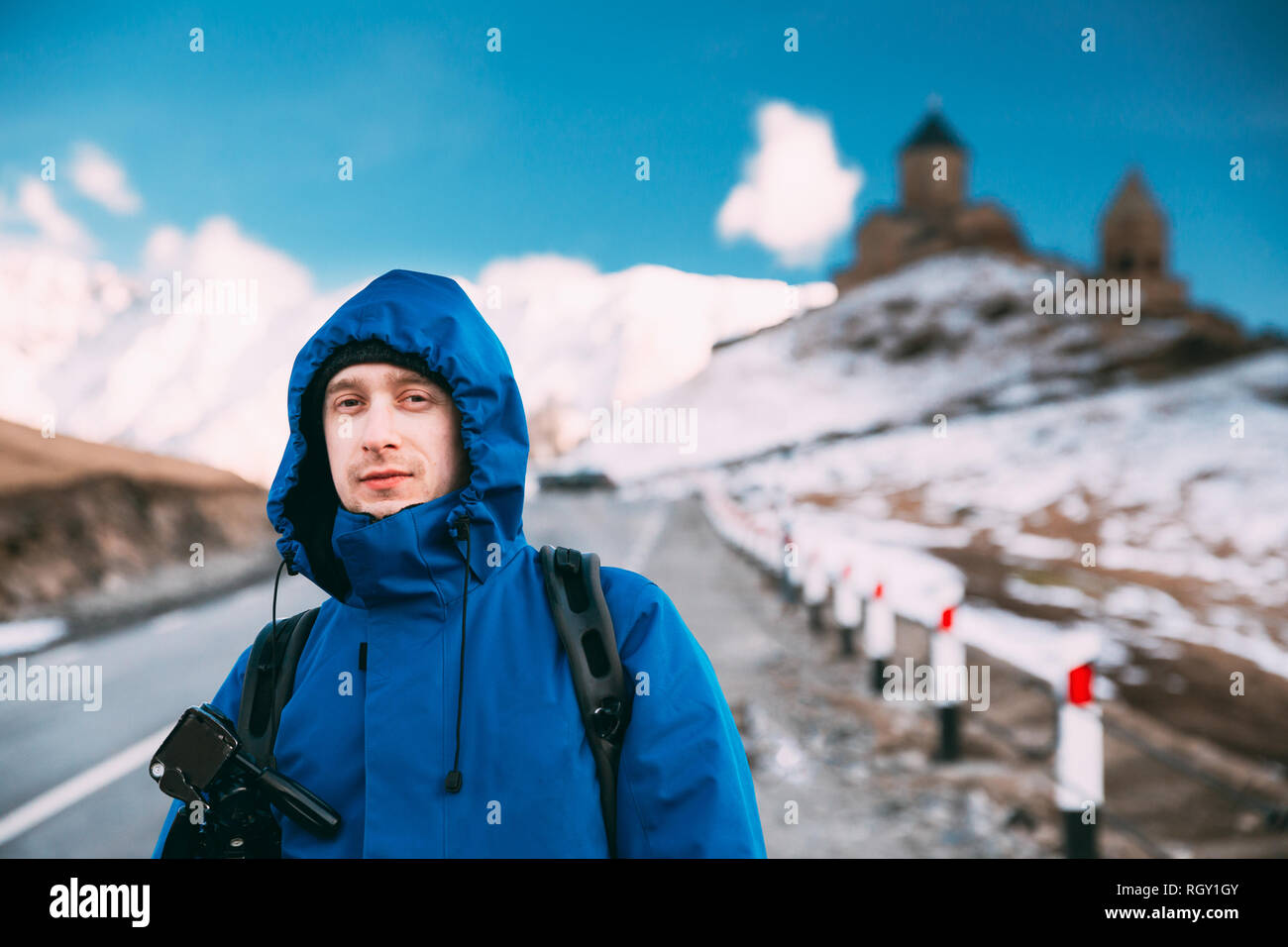 Stepantsminda Gergeti, Géorgie). Photographe Voyageur Backpacker touristiques homme posant près de l'église Holy Trinity - Tsminda Sameba. Belle Lan Géorgienne Banque D'Images