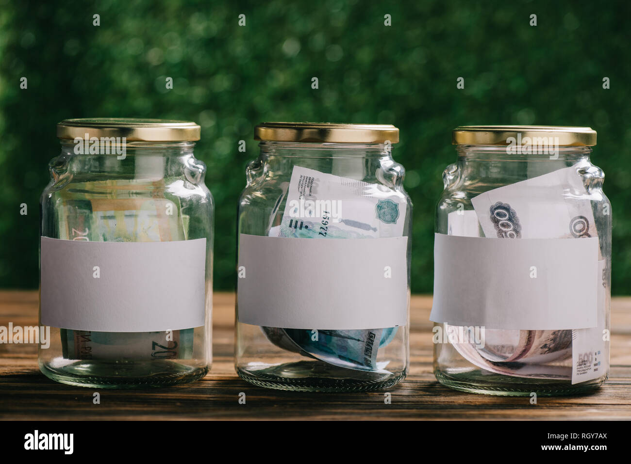 Les bocaux en verre avec des étiquettes vierges et roubles russes billets sur table en bois Banque D'Images