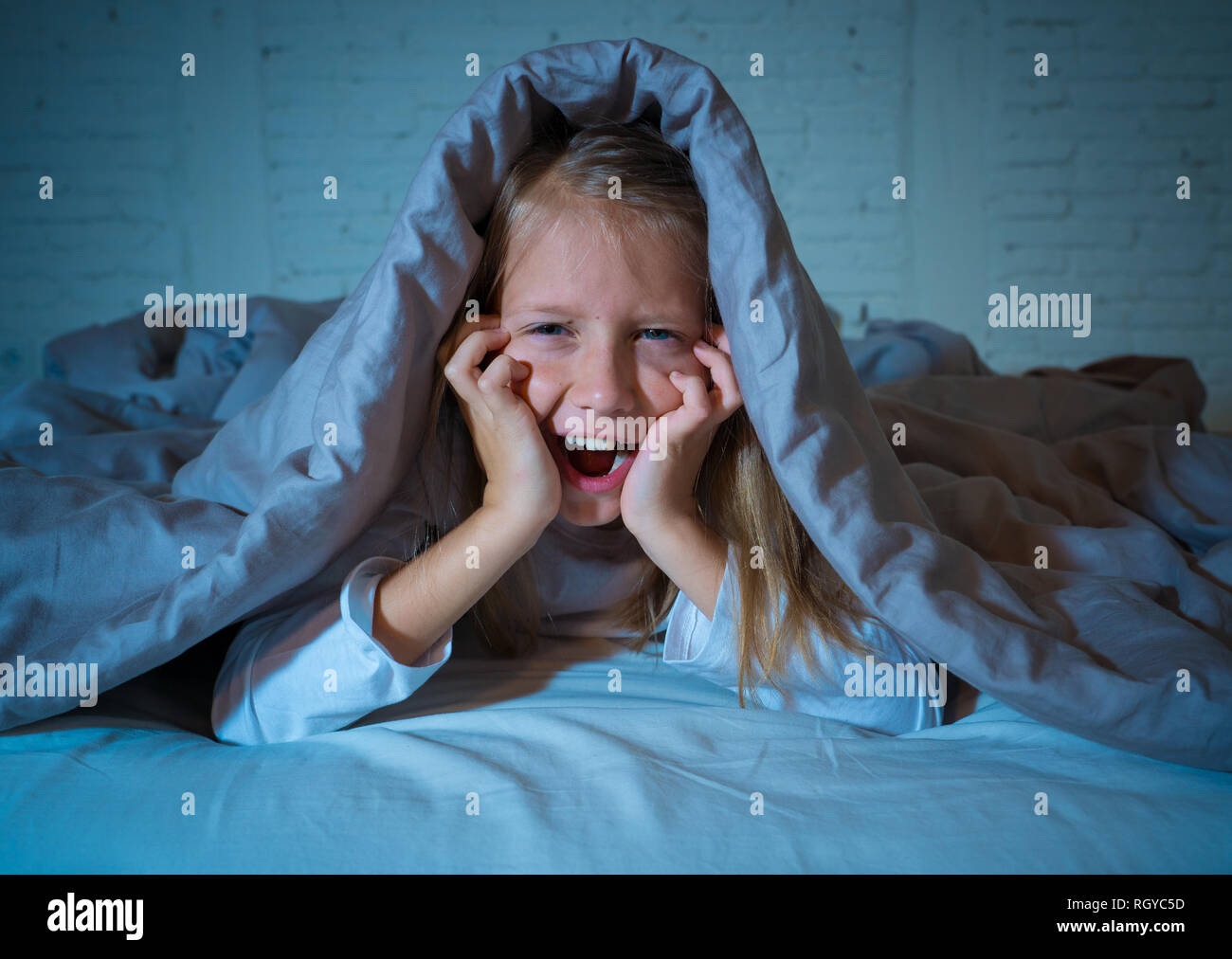 Cute girl endormi crier et pleurer après effrayant ou perturbants dream couvrant elle-même d'une couverture dans le lit la nuit d'humeur dans l'Éclairage dramatique Banque D'Images