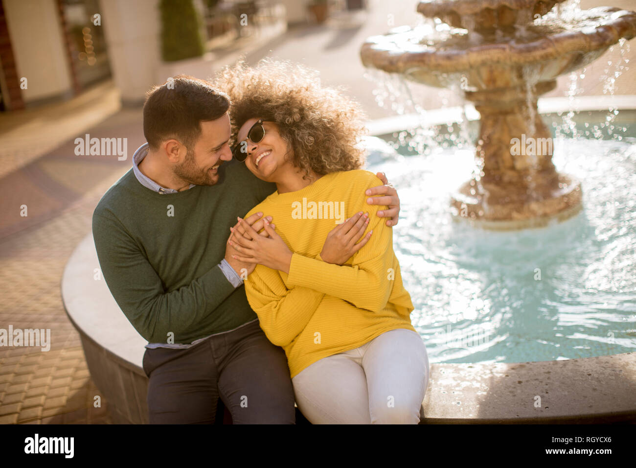 Portrait of beautiful smiling love couple assis près de la fontaine, un jour ensoleillé Banque D'Images