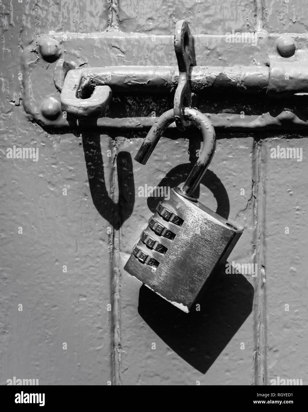 Un vieux cadenas déverrouillé sur une vis en noir et blanc Banque D'Images