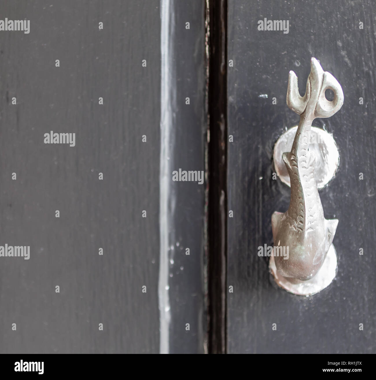 Heurtoir en laiton en forme de poisson monté sur une porte noire Banque D'Images