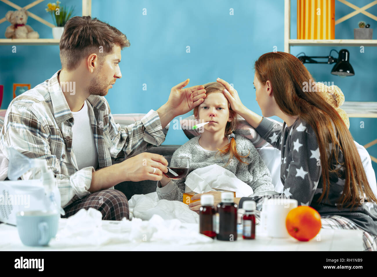 La jeune femme et l'homme avec fille malade à la maison. Le traitement à domicile. Le combat à la parodontose. Soins médicaux. IIlness la famille. L'hiver, la grippe, de la santé, de la douleur, de la parentalité, concept de relation Banque D'Images