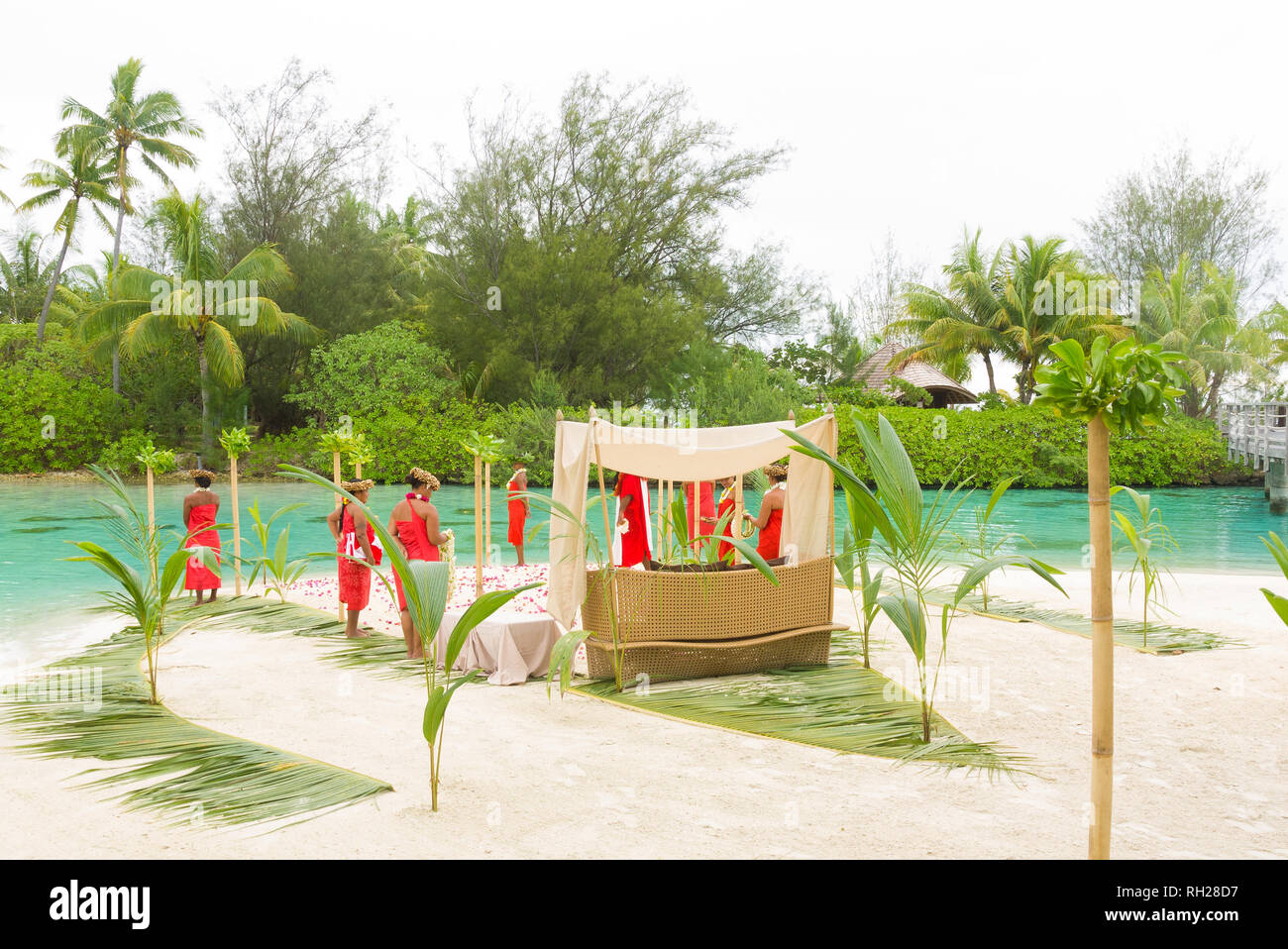 Les gens à préparer une cérémonie de mariage traditionnelle sur une plage de Bora Bora avec des frondes de palmiers et de bambous. Banque D'Images