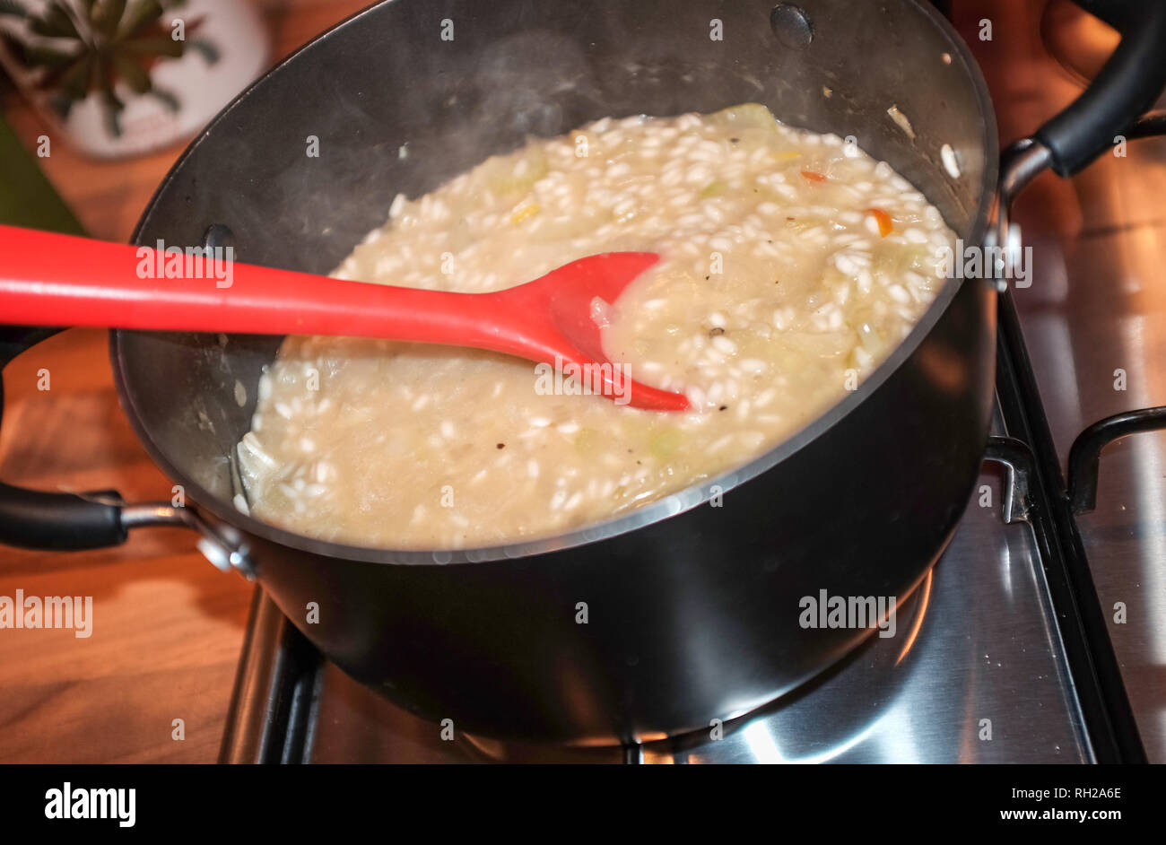 Accueil la cuisson en remuant une casserole faire risotto UK Banque D'Images