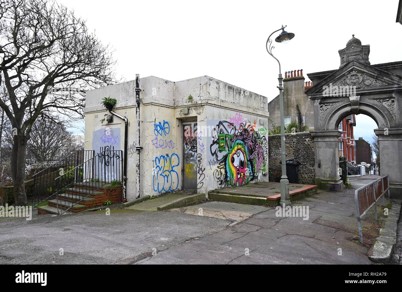 Couverts de graffitis et vandalisée ancienne anciennes toilettes publiques à l'entrée de Queens Park à Brighton East Sussex UK Banque D'Images