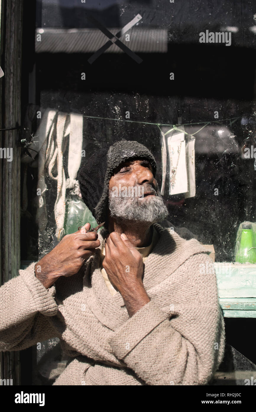 Un vieil homme tailler sa barbe avec le ciseau sur le bord de la route dans la vallée de Neelum, Azad Cachemire, Pakistan Banque D'Images