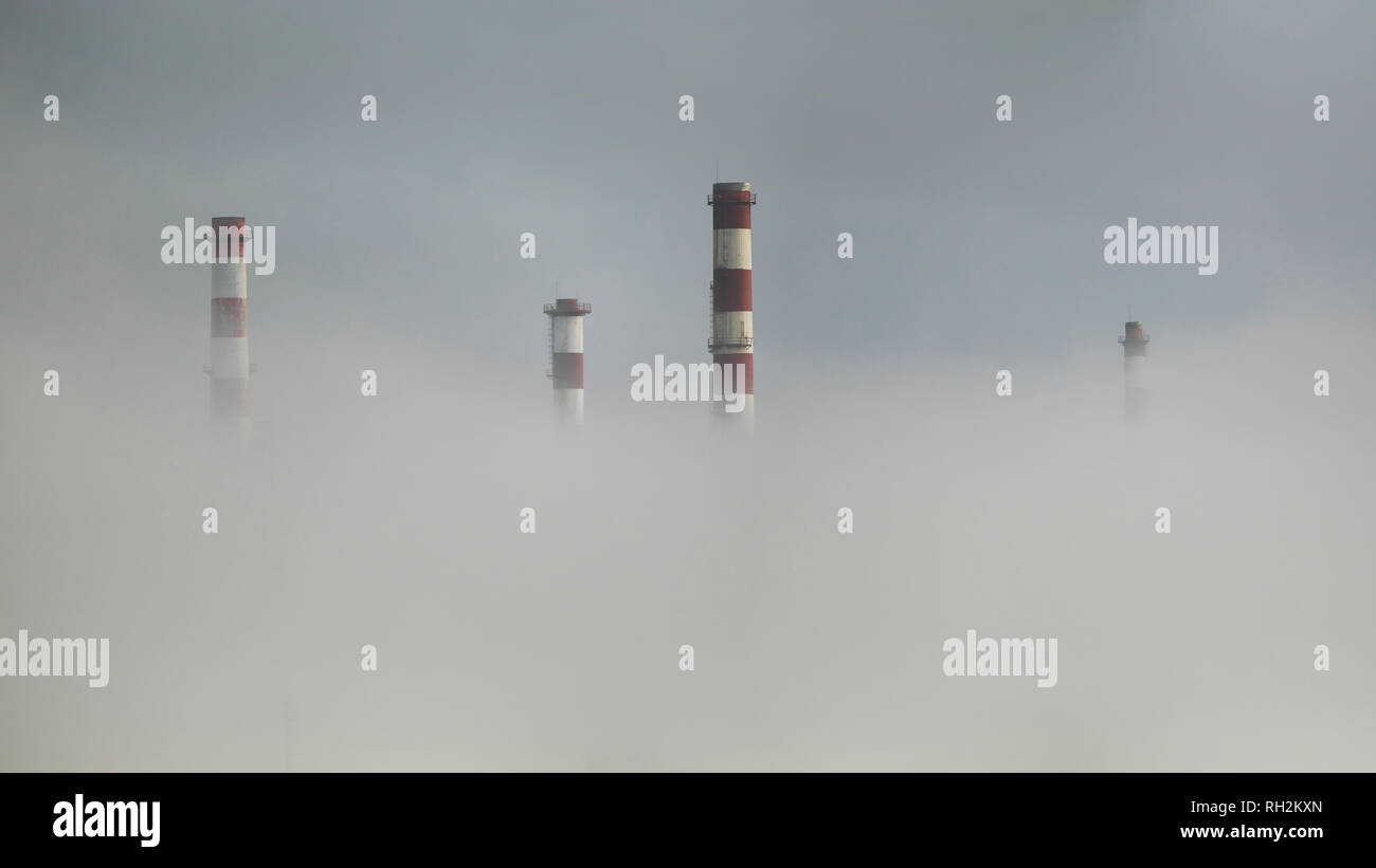 Les cheminées de la raffinerie de pétrole dans le brouillard semi losted Banque D'Images