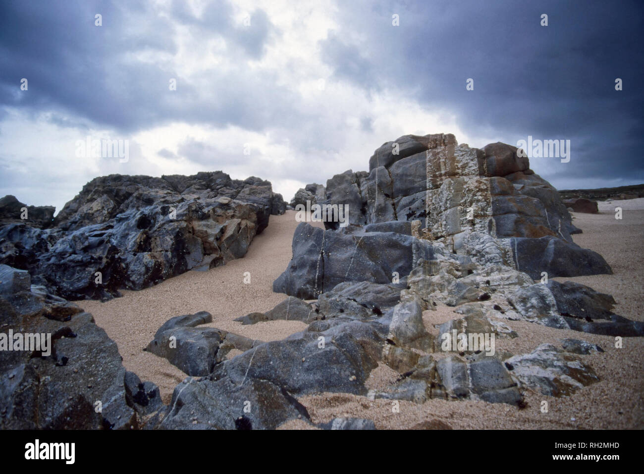 Les roches à rayures d'un portugais du nord plage éloignée durant la marée basse contre un ciel nuageux. Analogique : film 35 mm. Banque D'Images